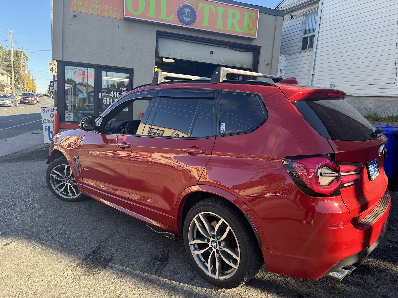 A red SUV parked outside the shop in front of the orange Cheapo Oil and Tire sign.